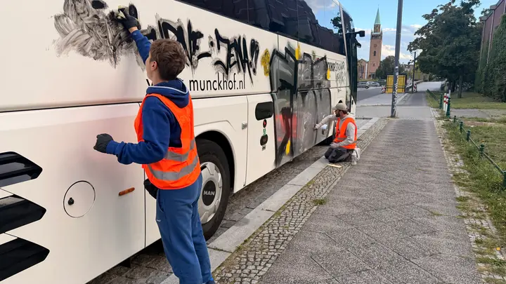 Manuelle Graffitientfernung an der weißen Karosserie eines Reisebusses bei einem separaten Immovate-Auftrag