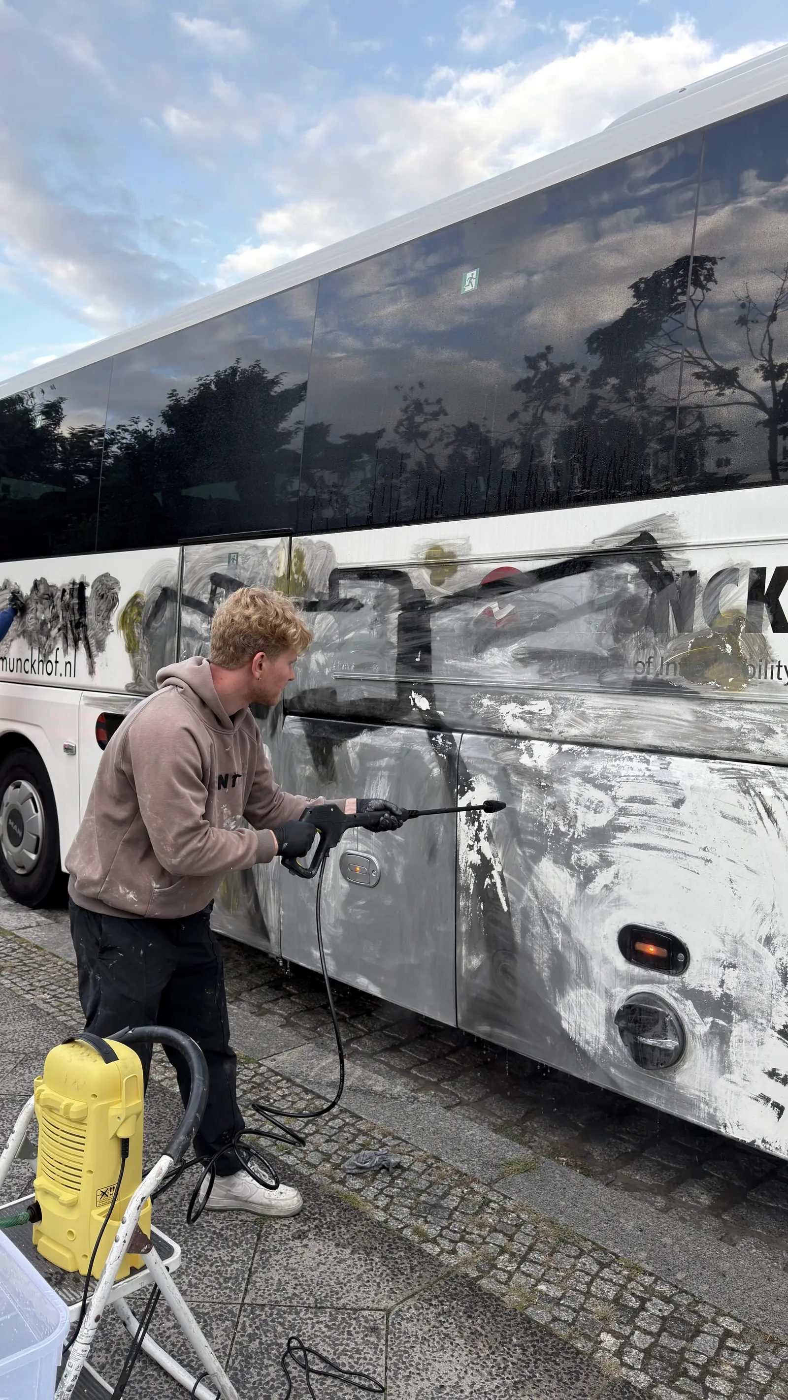 Immovate Mitarbeiter beim Abspülen gelöster Graffitifarbe von einer Busseitenwand