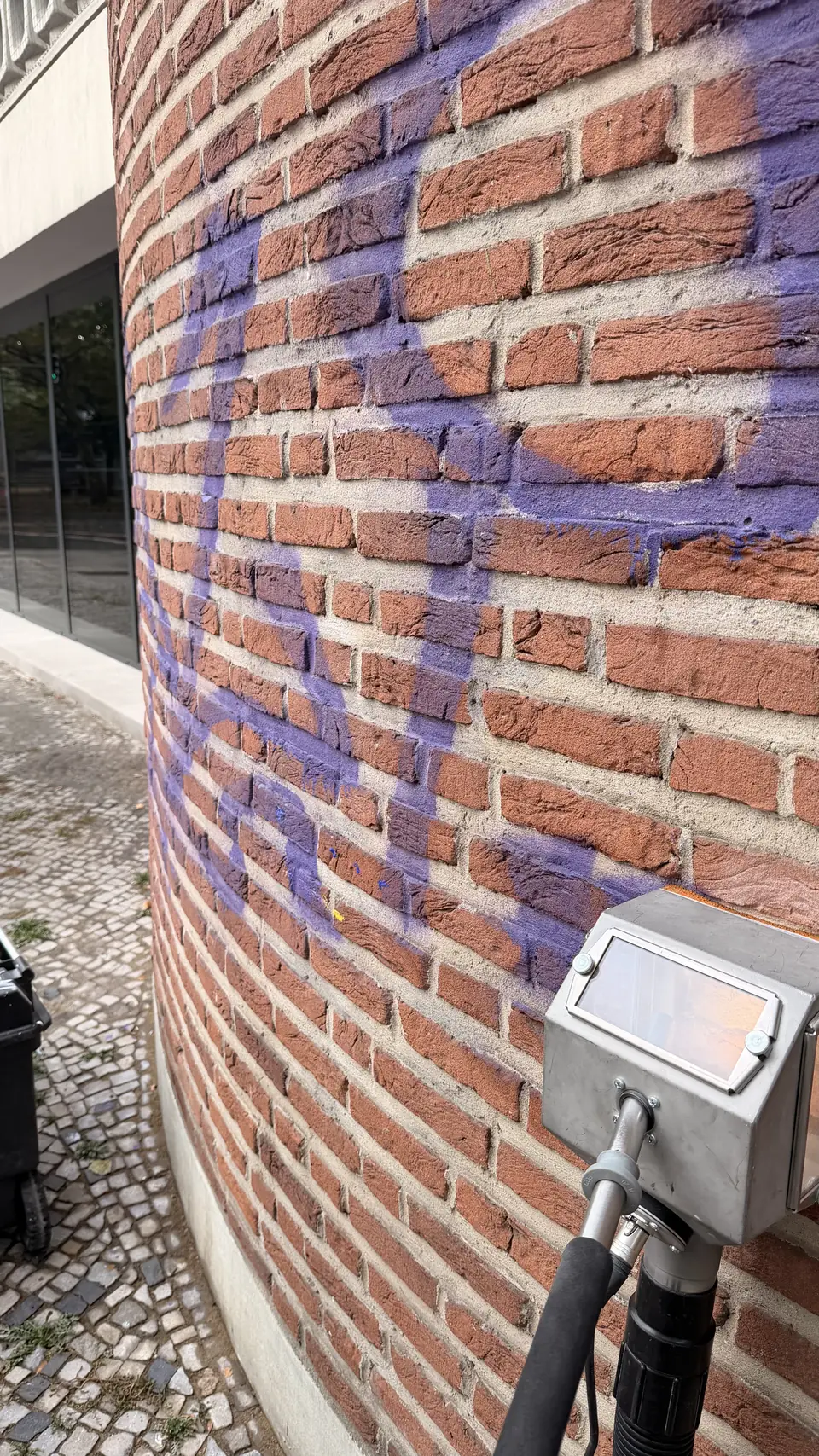 Tornado-ACS-Reinigungskopf an der rauen Backsteinfassade mit violettem Graffiti