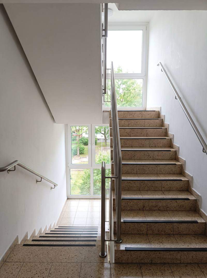 Sauberes Treppenhaus einer Wohnsiedlung in Berlin Spandau mit hellen Fliesen und Edelstahlgeländer