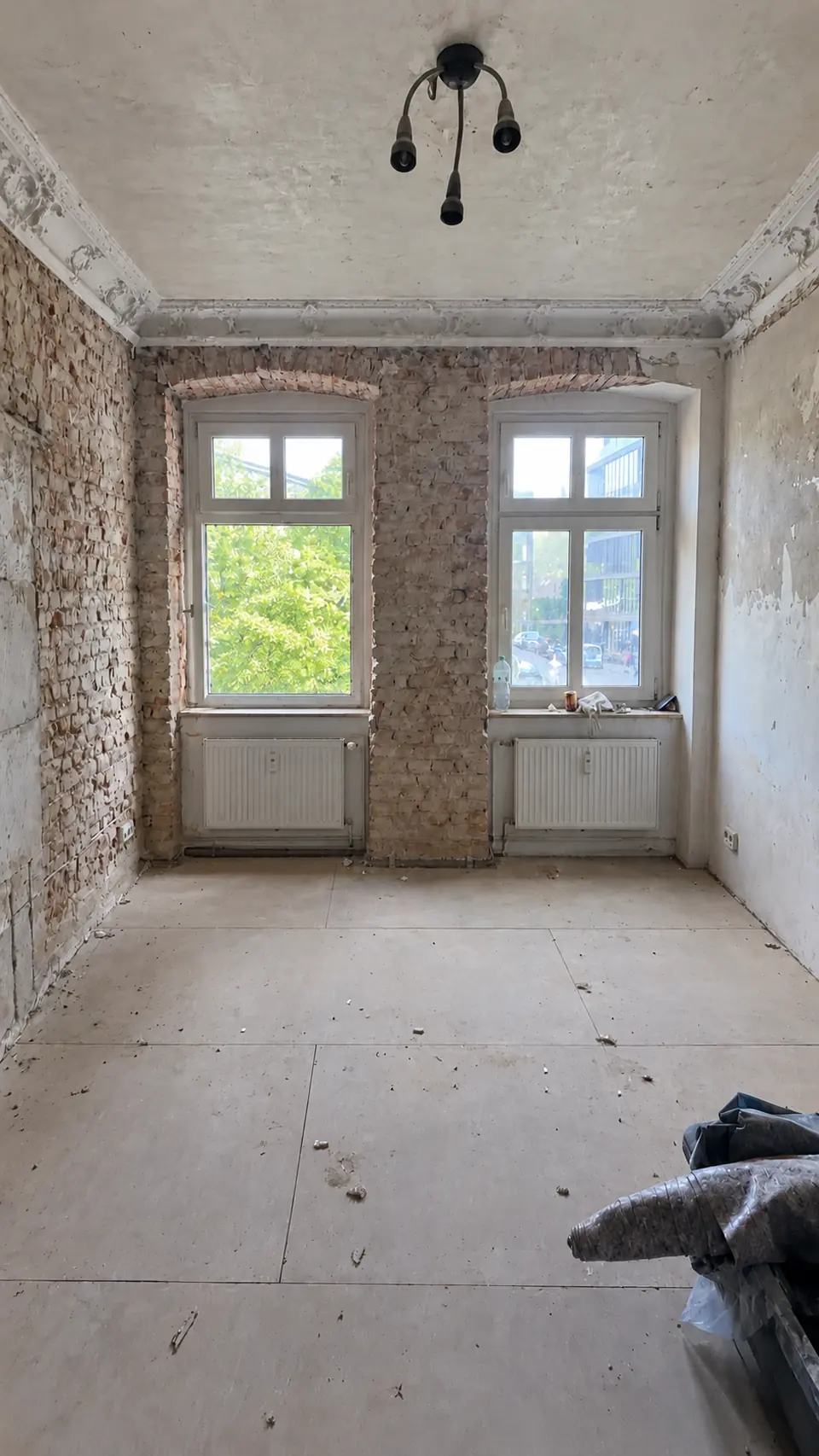 Wohnraum vor der Komplettsanierung in Berlin Mitte mit freigelegtem Backsteinmauerwerk